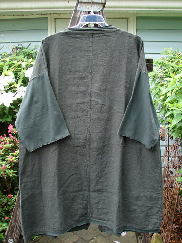 Barclay Cotton Sleeve Pocket Cardigan Unpainted Black Forest Size 1 displayed on a hanger, showcasing wooden buttons, drop shoulders, and front squared-off pockets with an upward curved hemline.