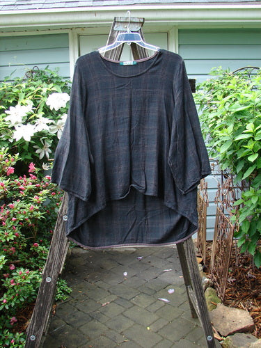 Barclay Linen Rayon High Low Tunic, Unpainted Black Plaid, Size 2, displayed on a clothes rack with plants in the background. Three-quarter sleeved design.