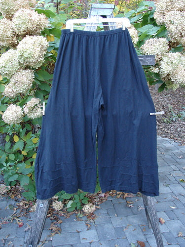 Barclay Two Pocket Pinch Cuff Wide Leg Pant Unpainted Black Size 2 displayed outdoors, featuring wide legs and elastic waist, framed by a rustic ladder against a backdrop of hydrangeas and stone paving.