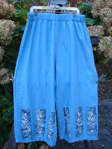 Barclay Linen Wide Leg Crop Pant Daisy Trio Cornflower Size 2 features light blue loose-fit culottes with a black-and-white floral motif on the hem, elastic waistband, and no pockets, embodying Bluefishfinder's vintage style.