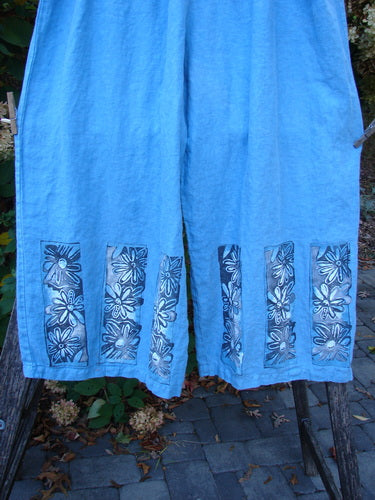 Barclay Linen Wide Leg Crop Pant Daisy Trio Cornflower Size 2 features light-blue capris with white daisy block prints on the hem, wide-leg design, and elastic waist, crafted from lightweight linen.