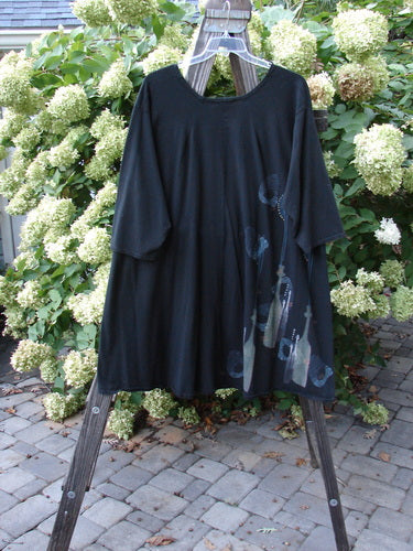 A black Barclay Hi Low Tunic Top with a tall neck bottle theme paint. Features include a soft neckline, varying hemline, and three-quarter length sleeves. Made from organic cotton. Size 2.
