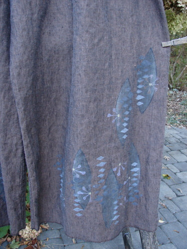 Barclay Cross Dye Linen Wide Leg Crop Pant Floral Sphere Wood Size 2, displayed outdoors, features a coarse linen fabric with blue leaf patterns. The design highlights a relaxed fit and wider cropped length.