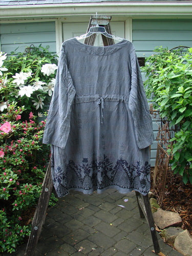 Barclay Linen Rayon High Low Tie Back Dress Shadow Border Night Sky Size 2 hanging outdoors, showcasing its long sleeves and elegant design on a wooden post.