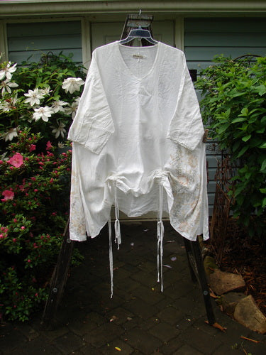 Barclay Linen Venetian Vented Tunic Dress Soft Side Floral White Size 2 displayed on a wooden swing, showcasing its three-quarter sleeves and elegant design.