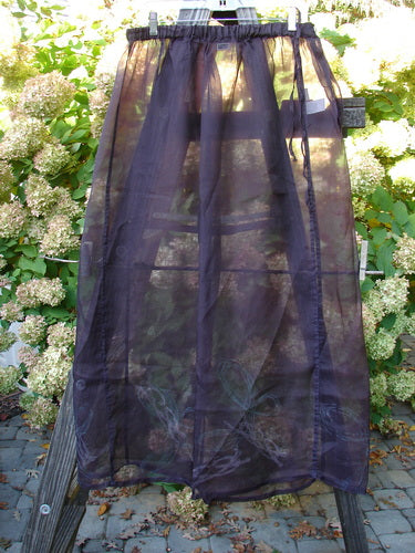 2000 Silk Organza Skirt Wind Whisp Aubergine Size 1 draped over a wooden stepladder, showcasing its semi-transparent, flowing design with vertical sectional panels, ideal for expressing individual style.
