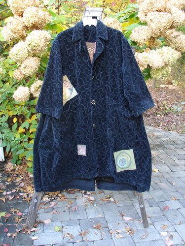 1998 Patched Tapestry Coat Bountiful Sun Guy Black OSFA hangs elegantly, showcasing a swirling damask pattern with unique appliqué patches. Features a stand-up collar, angular pockets, and a flowing A-line silhouette.
