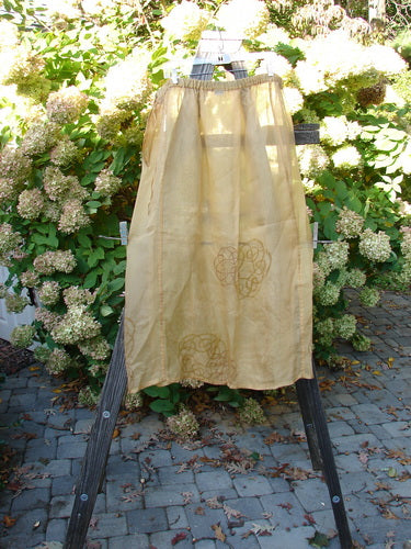 2000 Silk Organza Skirt Wind Turn Bone Size 2: A yellow cloth skirt on a wooden stand, featuring a lined flare and vertical exterior panels.
