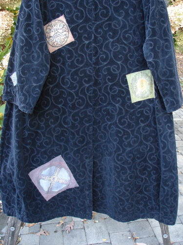 1998 Patched Tapestry Coat Bountiful Sun Guy Black OSFA, featuring velvet-like dark-blue fabric with swirling motifs, adorned with pastel appliqué patches of sun, shell, starfish, and flower, hanging on a wooden frame.