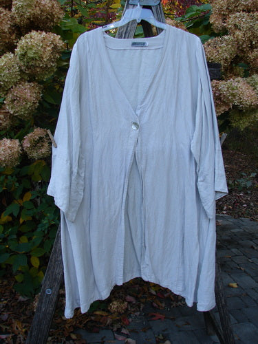 Barclay Hemp Silk Single Button Cardigan Unpainted Dew Size 2, featuring a deep V-neckline, wide banded sleeves, and a single shell button, elegantly drapes on an outdoor frame.