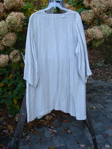 Barclay Hemp Silk Single Button Cardigan Unpainted Dew Size 2 displayed outdoors on a hanger, highlighting its deep V-neckline, wide-banded sleeves, and curved seams, perfect for creative expression and vintage style.