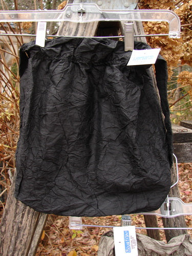 A 2000 NWT Shaunting Silk Bag in unpainted black, showcasing its elastic-topped closure and crinkled silk texture, hangs outdoors, highlighting its lightweight, dressy appeal from Bluefishfinder.com.
