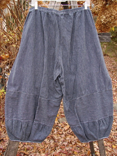 Barclay Hemp Cotton Meadow Pant Unpainted Black Stripe Size 1, featuring loose, baggy bloomers style with elastic waist and gathered cuffs, displayed outdoors against dried leaves and wooden ladder. Perfect for spring or summer.