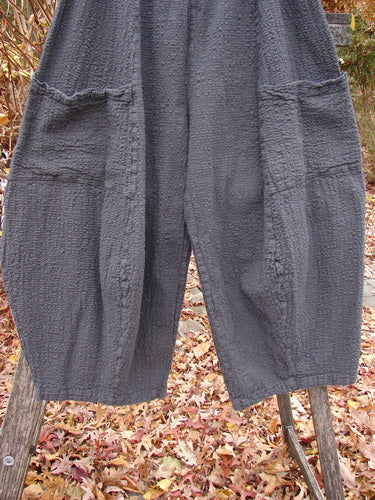Barclay Pucker Crop Mojo Pant Unpainted Ironworks Size 1 features loose-cut, charcoal-gray trousers with a textured cotton design, 3D diamond-shaped tapering, large patch pockets, and a thick elastic waistband, set outdoors.