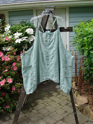 Vintage Barclay Linen Drop Pocket Apron in Seafoam, Size 2, hanging outdoors. Features adjustable straps, drop sides, and double front pockets. Unpainted for layering. Perfect for expressing creativity.