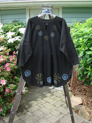 1997 Masquerade Top Celtic Continuum Obsidian OSFA: A vintage black shirt with a flower design, featuring a teardrop neckline, rounded hemline, and draw cord back. From BlueFishFinder's unique collection of Vintage Blue Fish Clothing.