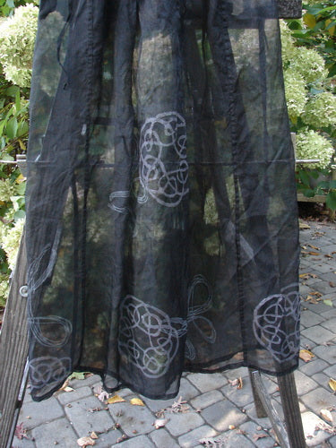 2000 NWT Silk Organza Skirt: A black skirt with a patterned design. Made from silk organza, it features a lined flare, elastic waistline, and waist vent. The skirt has vertical exterior panels and a sheer plum hue. The measurements are waist 32, hips 56, sweep 66, and length 40 inches.