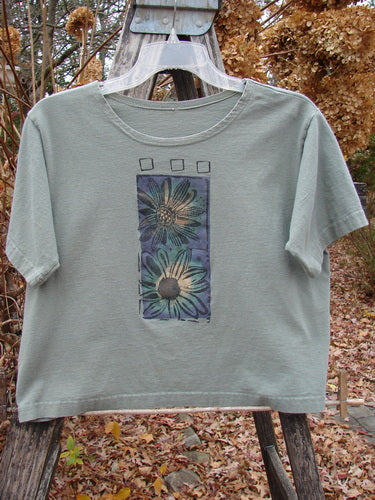 1996 Crop Tee Floral Butterfly Cricket Size 1 features a cropped, boxy silhouette with a vertical daisy print and butterfly theme, short sleeves, and a gently rolled neckline, hanging outdoors.