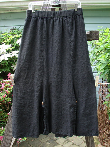 Alt text: Barclay Linen Double Button Back Vent Skirt Unpainted Black Size 2 hanging on a clothesline, showcasing its full elastic waistline and unique front double button vents.