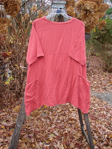 Barclay Gauze Two Pocket Urchin Dress Unpainted Geranium Stripe Size 1 hangs on a wooden ladder, showcasing its loose fit, round neckline, short sleeves, and side pockets amidst an autumnal outdoor setting.