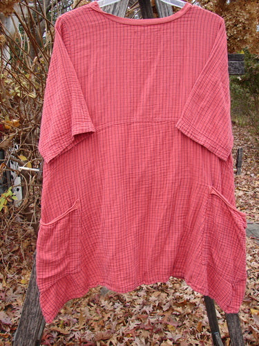 Barclay Gauze Two Pocket Urchin Dress Unpainted Geranium Stripe Size 1 draped on a hanger outdoors, features a loose fit, scooped neckline, short sleeves, subtle plaid pattern, and front hip patch pockets.
