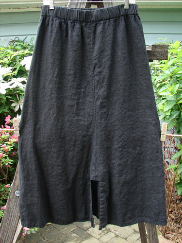 Barclay Linen Double Button Back Vent Skirt Unpainted Black Size 2 displayed on a clothes rack, showcasing its full elastic waistline, front double button vents, and rear kick vent.
