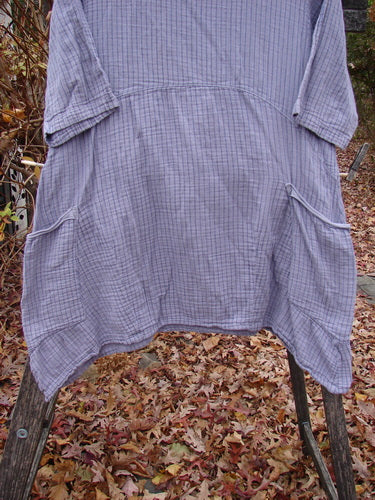 Barclay Gauze Two Pocket Urchin Dress Unpainted Light Plum Stripe Size 1 displayed outdoors on a wooden ladder, showcasing its unique flutter neckline and three-quarter sleeves against a backdrop of fallen autumn leaves.