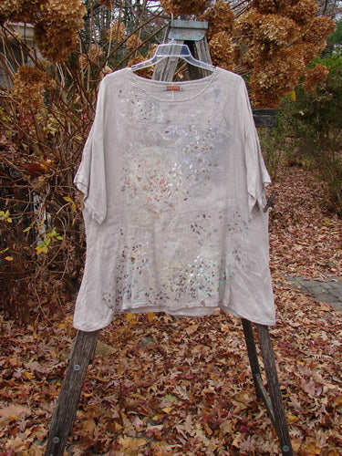 Barclay Lightweight Linen Tea Time Top Fall Rain Sand Size 1 draped on a stepladder; features a distressed, mottled texture with bleach spots, three-quarter sleeves, and a flowy A-line shape.