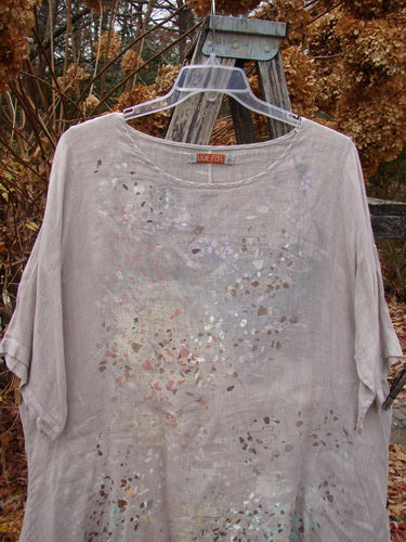 Barclay Lightweight Linen Tea Time Top Fall Rain Sand Size 1, featuring a flowy A-line shape with a varying hemline and three-quarter sleeves, displayed on a clear hanger against a rustic ladder.