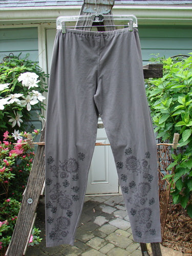 A pair of Barclay Cotton Lycra Legging Botanicals Grey Plum Size 2 hanging on a clothesline, featuring a floral design, relaxed fit, and longer leg length.