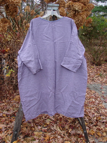 Barclay Linen Oversized Gallery Dress Home Fall Violet OSFA hangs on a wooden ladder outdoors, showcasing its loose, tunic-like shape with three-quarter dolman sleeves and a rounded neckline, capturing a vintage aesthetic.