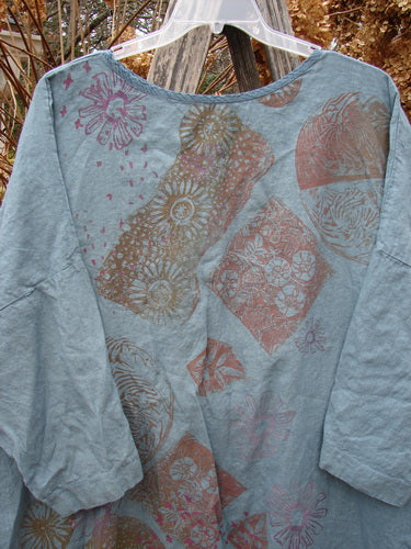 Barclay Linen Oversized Gallery Dress Falling Daisy Delaware OSFA features a loose, light blue-gray tunic with block-print motifs in earth tones, elbow-length sleeves, and a rounded neckline, embodying vintage Blue Fish style.