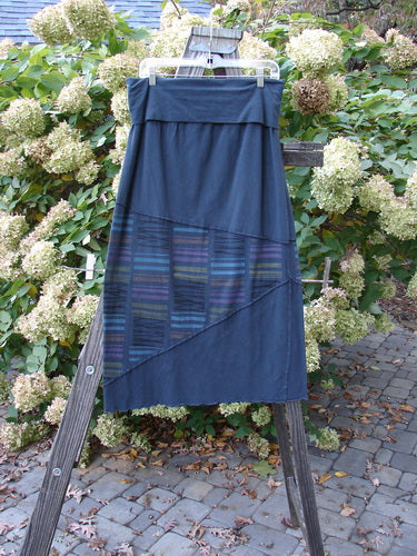 A Barclay Fold Over Column Skirt in Stripe Blue Mineral. Features include a fold over waist panel, exterior zig zag stitchery, and stripe triangular accents. Made from organic cotton with a touch of lycra. Measures 32" by 8" (panel) and 42" (hips), with a full length of 40".