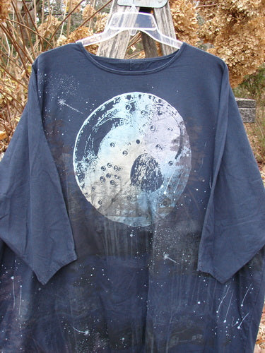 Barclay Cotton Lycra Flutter Hem Dolman Pullover Centered Ink OSFA features a cosmic moon and stars design, hanging outdoors on a wooden structure, showcasing its boxy shape, dolman sleeves, and fluttered hemline.