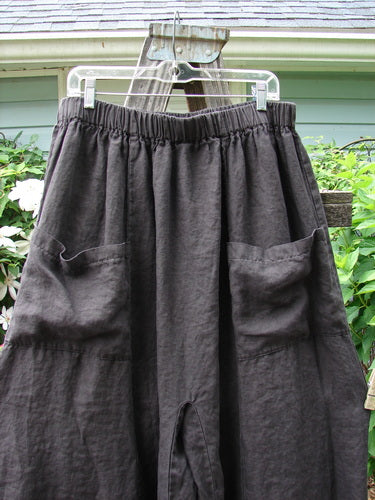 A black Barclay Linen Crop Wide Leg Pocket Pant with a thick elastic waist and oversized pockets hanging on a clothes hanger.