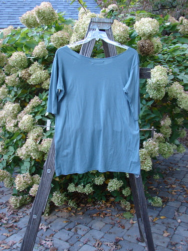Image: A blue shirt on a wooden rack.

Alt text: Barclay Batiste Raw Edge Tee Top Unpainted La Mer Size 1 on wooden rack.