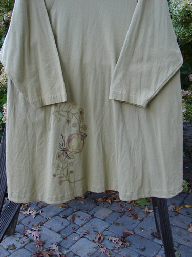 1998 Botanicals Bell Flower Top Root Berry Seed Size 2: A long sleeved shirt on a rack. Lovely belled A-line shape with a softly rounded neckline. Features significant sectional panels and a blue fish signature patch. Made from organic cotton.