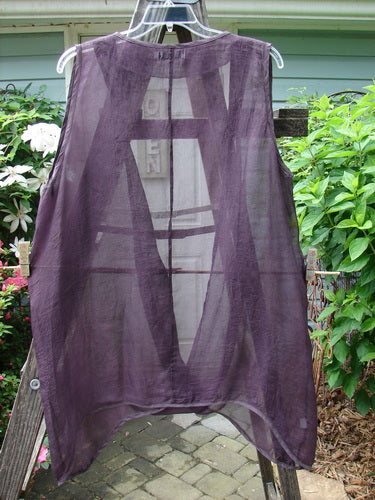 Barclay Silk Infinity Twist Pullover Unpainted Rich Plum Size 2 displayed on a clothes rack, featuring unique open front twist, deeper arm openings, and varying hemline design.