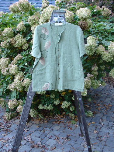1998 Botanicals Robin's Top: A green shirt with flowers on a swinger. Features include a smaller back shoulder line, A-line shape, elastic-topped pockets, and perfect buttons. Made from heavy-weight linen. Size 1.