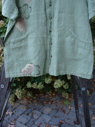 1998 Botanicals Robin's Top, a green shirt with pockets. Slightly smaller back shoulder line, super A-line shape. Darling dual front elastic-topped and rounded bottom pockets. 7 tiny perfect buttons. Mixed garden theme paint on thick weighted linen. Bust 46, waist 48, hips 50, hem circumference 54. Length is 27 inches.