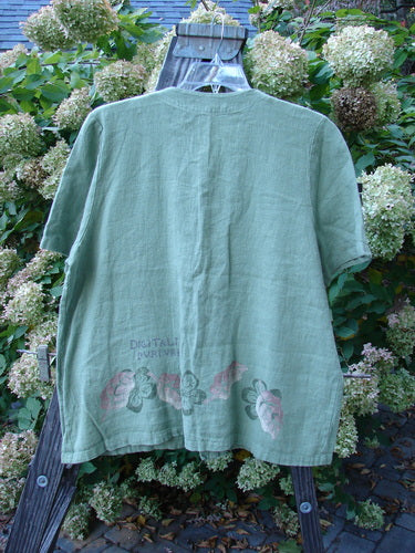 1998 Botanicals Robin's Top: A green shirt with flowers on it, featuring a slightly smaller back shoulder line, a super A-line shape, and darling dual front elastic-topped and rounded bottom pockets. Made from heavy-weight linen, this top is a perfect addition to your collection.