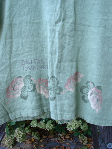 1998 Botanicals Robin's Top, a close-up of a cloth with a plant and flower. Perfect condition, heavy weight linen. Features include a smaller back shoulder line, A-line shape, elastic-topped pockets, and tiny buttons. Bust 46, waist 48, hips 50, hem circumference 54, length 27.