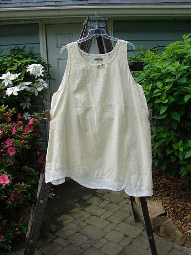 Barclay NWT Hemp Cotton Empire Flutter Pinafore Unpainted Creme Size 2 displayed on a hanger, showcasing its asymmetrical hemline, rounded neckline, and diagonal bust darts.