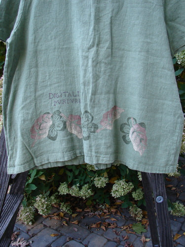 1998 Botanicals Robin's Top: A green shirt with pink flowers, featuring a smaller back shoulder line, elastic-topped pockets, and perfect buttons. Made from heavy-weight linen, this darling top is from the Botanicals Collection of 1998 in Elm. Bust 46, Waist 48, Hips 50, Hem Circumference 54, Length 27.