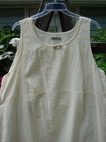 A white Barclay NWT Hemp Cotton Empire Flutter Pinafore Unpainted Creme Size 2 displayed on a hanger, showcasing its rounded neckline, asymmetrical hemline, and wide arm openings.
