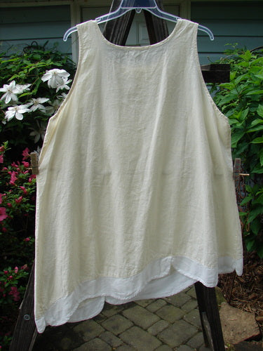Barclay NWT Hemp Cotton Empire Flutter Pinafore Unpainted Creme Size 2 displayed on a clothes hanger, showcasing its sweetly rounded neckline and asymmetrical hemline with white scallop flutter details.