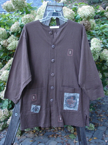 1996 Everyday Jacket Inner Woman Molasses Size 2: A brown shirt with patches on it, featuring a longer shape, scribe buttons, oversized exterior painted drop pockets, and a Blue Fish patch.