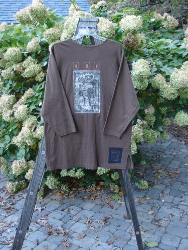1996 Everyday Jacket Inner Woman Molasses Size 2: Long-sleeved brown shirt with a face on it. Features include scribe buttons, oversized exterior painted drop pockets, and a Blue Fish patch.