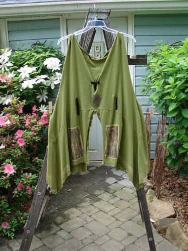 Vintage 1993 Holy Vest Mythical Door Olive Size 2 by BlueFishFinder: Green pants hanging on a clothesline, surrounded by plants and flowers, embodying the creative freedom of Jennifer Barclay's iconic Blue Fish Clothing line.