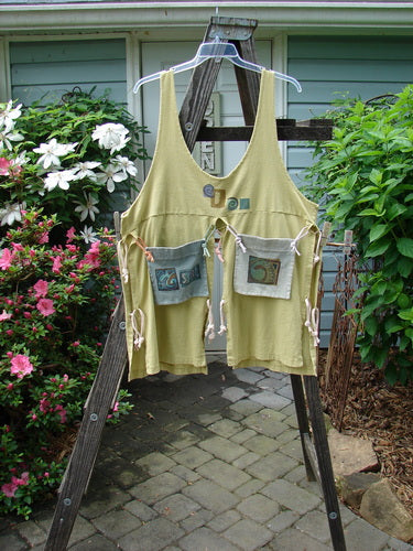 Vintage 1996 4 Corner Pocket Apron from Key Lemon on a ladder, featuring a unique geo theme paint. Made of organic cotton, with oversized tie-on pockets and rippie accents. Perfect for creative self-expression.